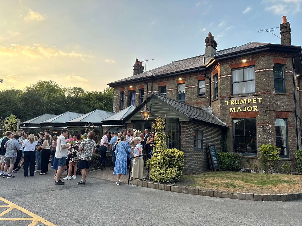 People gathered outside Trumpet Major, socialising under a blue sky.
