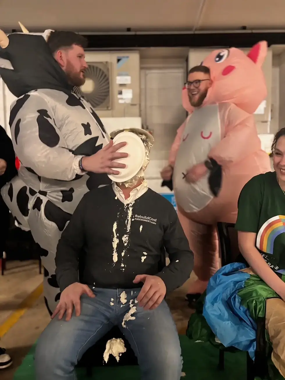 RiskSTOP Group colleagues in cow and pig costumes laugh as a team leader has a pie smashed in their face.