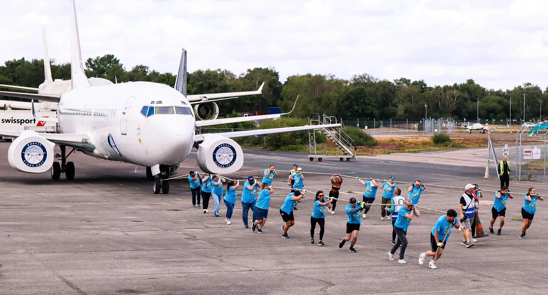 Full Flight Risk team pulling the Boeing 737 down the tarmac. Shot taken from afar, showing the sheer size of the aircraft.