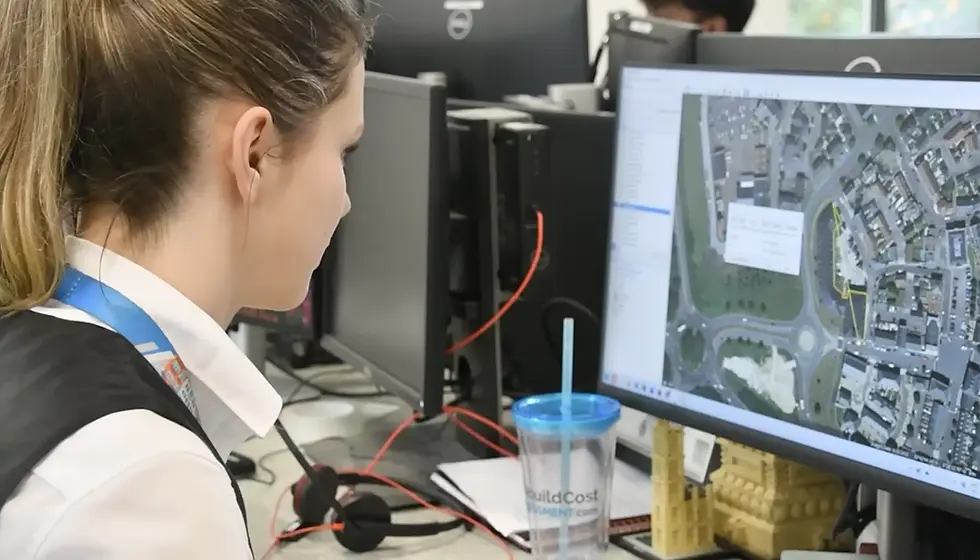 Woman at desk analysing a map on a computer screen, in an office setting.